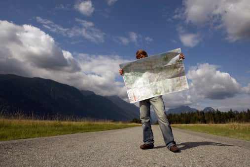 Image of man standing on rural road reading road map