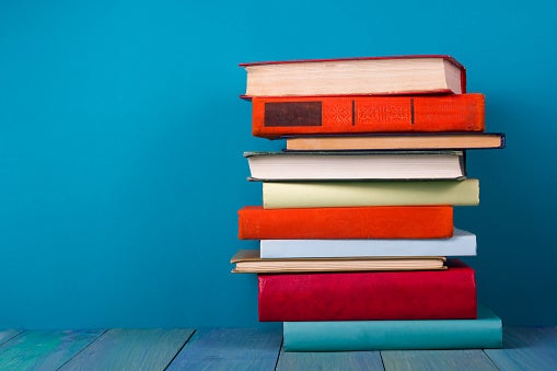 Image of stack of colorful books, grungy blue background, free copy space
